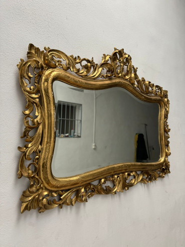 Elegante espejo dorado en oro fino con detalles cincelados en el marco.