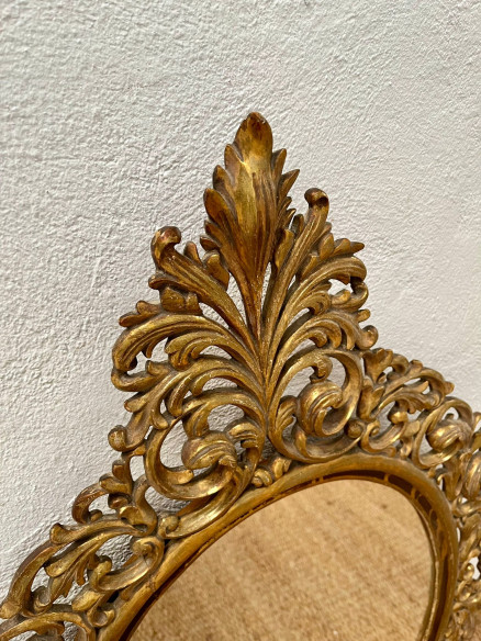 Espejo ovalado con bonito marco finamente tallado y dorado.