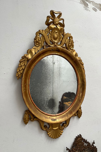 Elegante espejo ovalado dorado en oro fino.