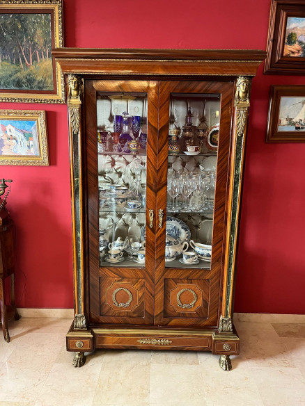 Vitrina estilo imperio con adornos en bronce, cristales biselados y capitoné.
