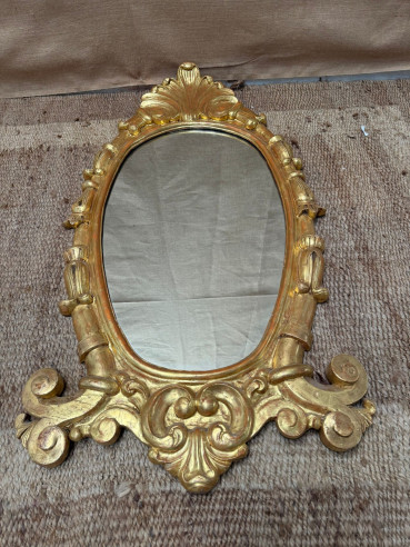 Elegante espejo tallado en madera y dorado en oro fino.