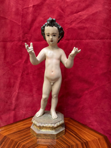 Niño Jesús tallado en madera sobre peana dorada.
