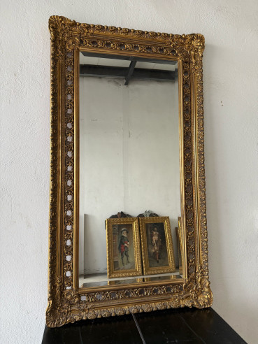 Espejo biselado con marco de madera dorado con orificios.
