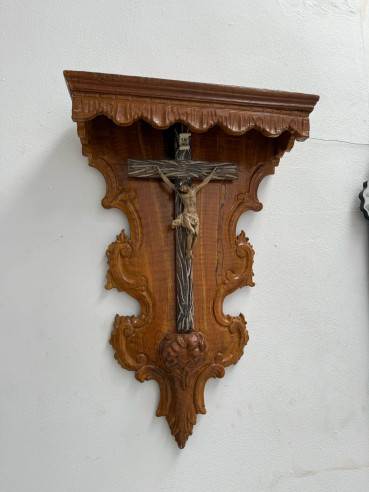Crucifijo de pared sobre cornucopia o tabernáculo tallado en madera.