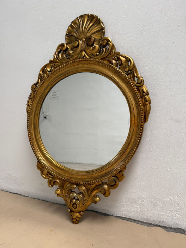 Elegante espejo en madera con volutas talladas alrededor.