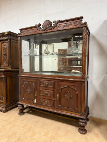 Elegante vitrina con cristales y balda con puertas laterales.