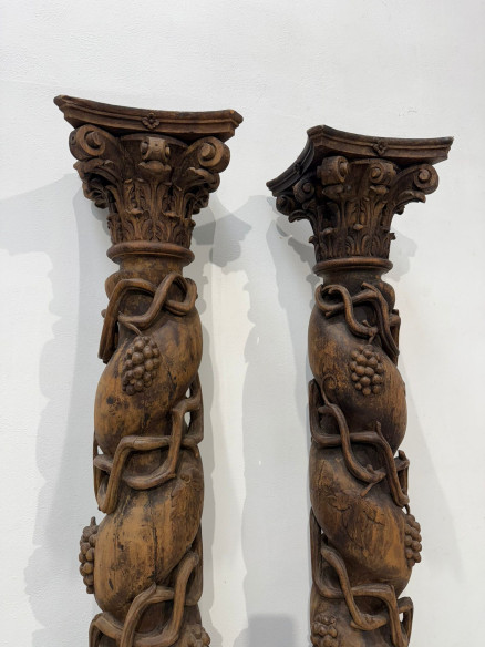 Pareja de columnas talladas en madera con racimos de uva.