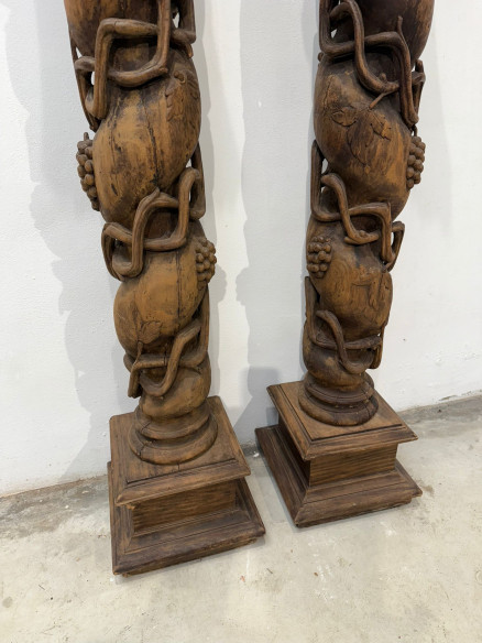 Pareja de columnas talladas en madera con racimos de uva.
