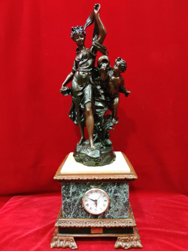Figura de mujer y niño sobre reloj de mármol