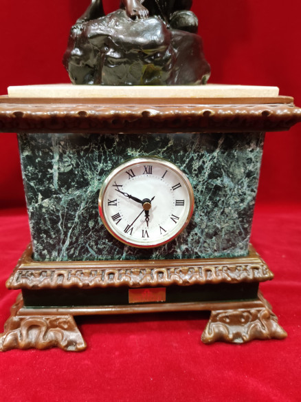 Figura de mujer y niño sobre reloj de mármol