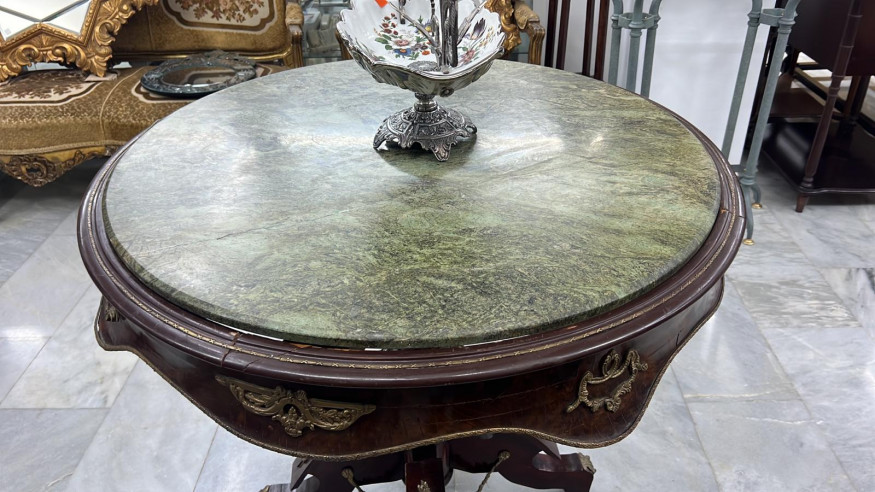 Mesa con adornos en bronce y tapa de mármol verde.